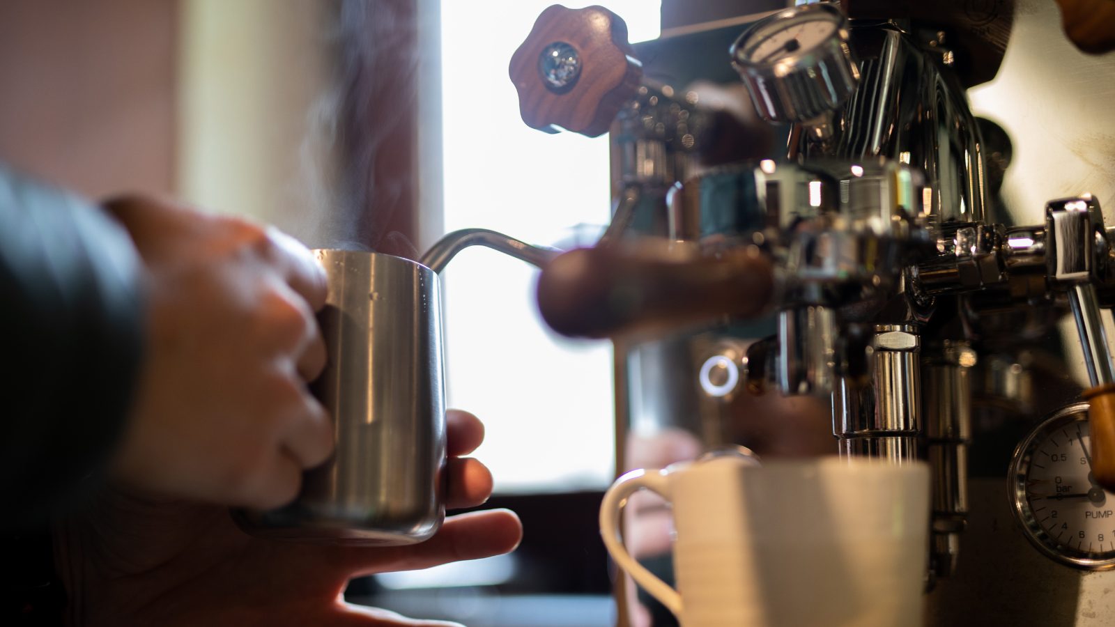 A barista steams milk at an espresso machine