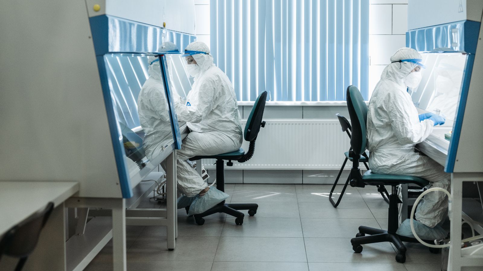 Two technicians in clean-room suits working at lab benches