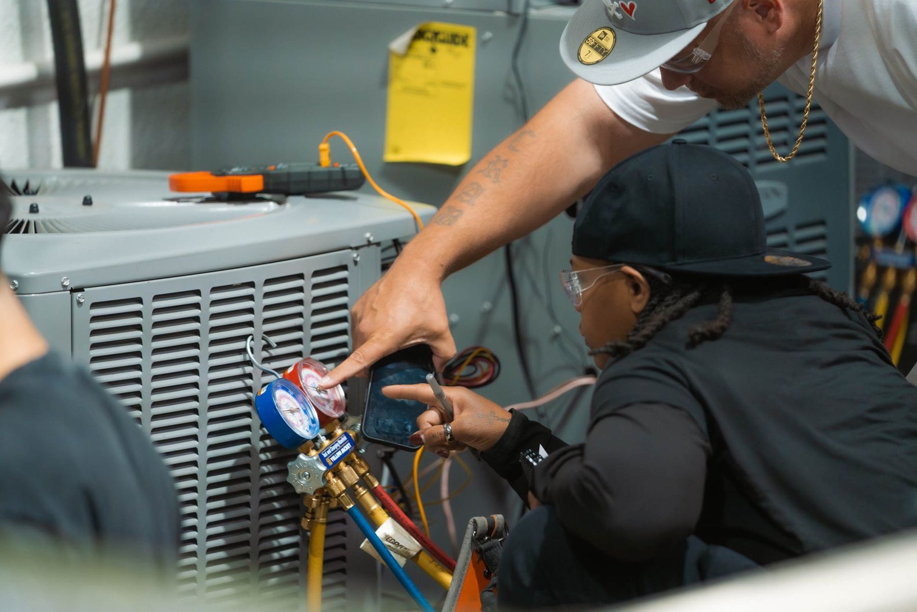 An NTI instructor points out a reading on refrigerant gauges to a student in the HVAC lab
