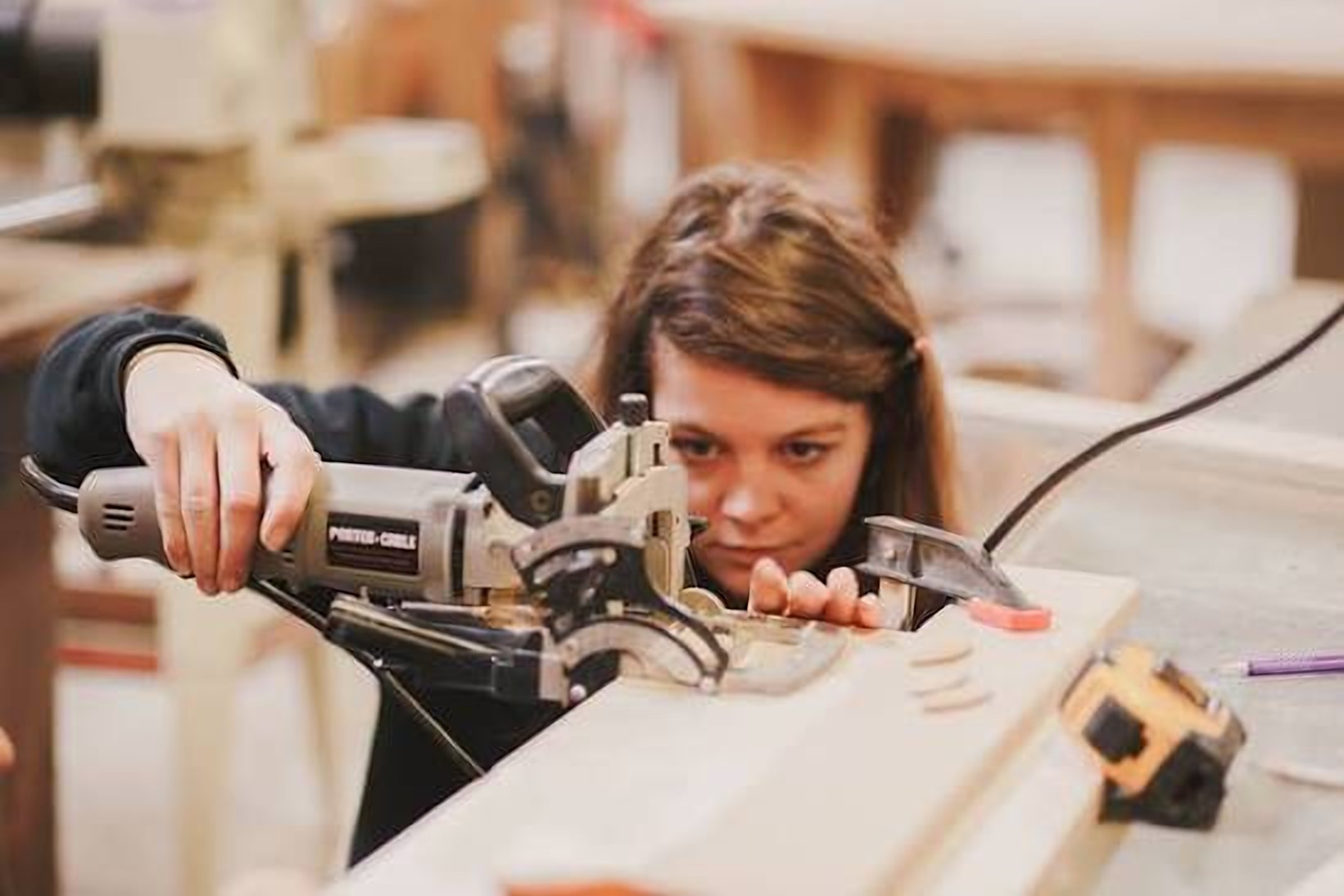 A woman lines up a cut with a jointer in the wood shop