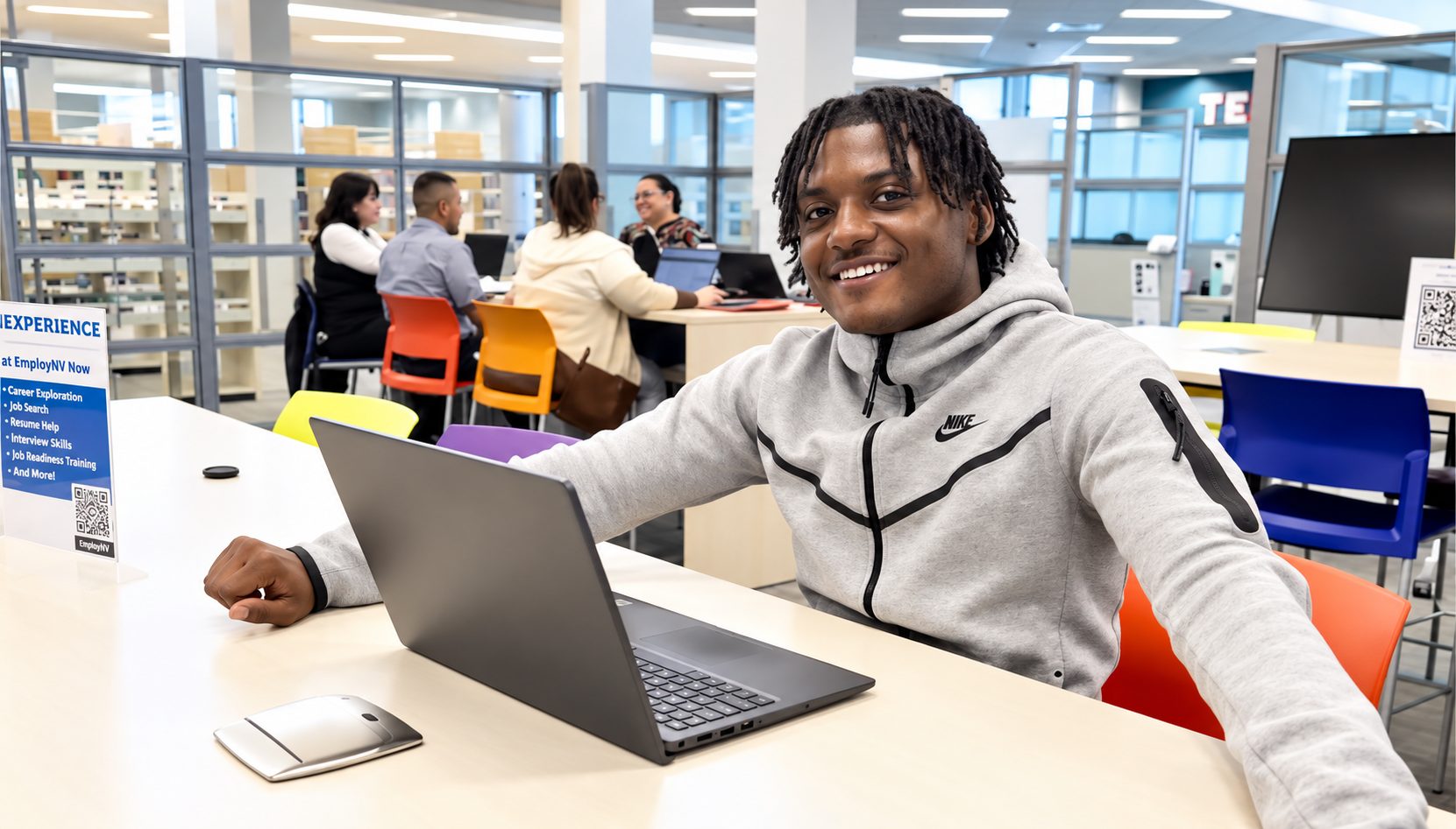 A young man smiles at a laptop in the EmployNV Career Hub